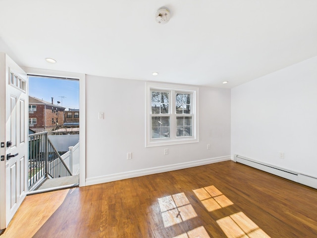 unfurnished room with baseboard heating, recessed lighting, baseboards, and wood finished floors