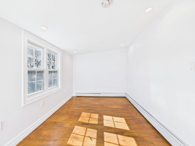 unfurnished room with a baseboard heating unit, recessed lighting, wood finished floors, and baseboards