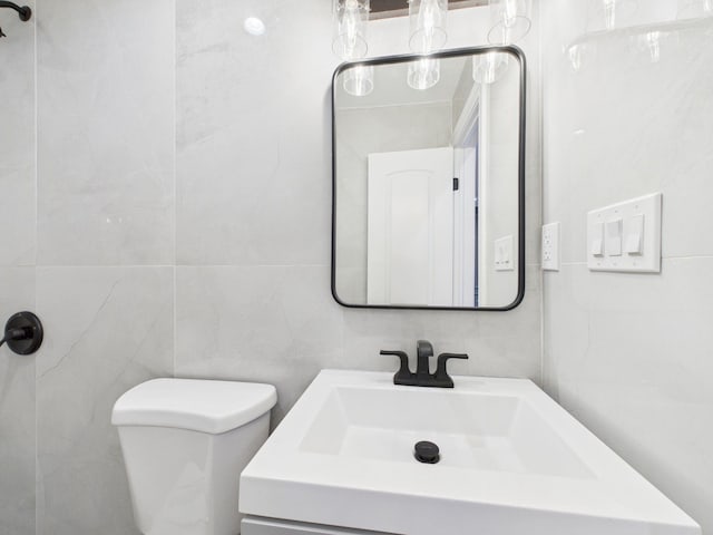 bathroom with vanity, toilet, and tile walls