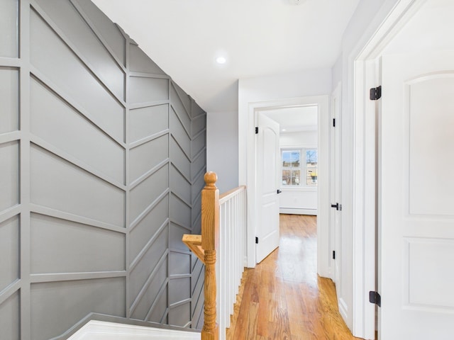 hallway with light wood finished floors, a decorative wall, and recessed lighting