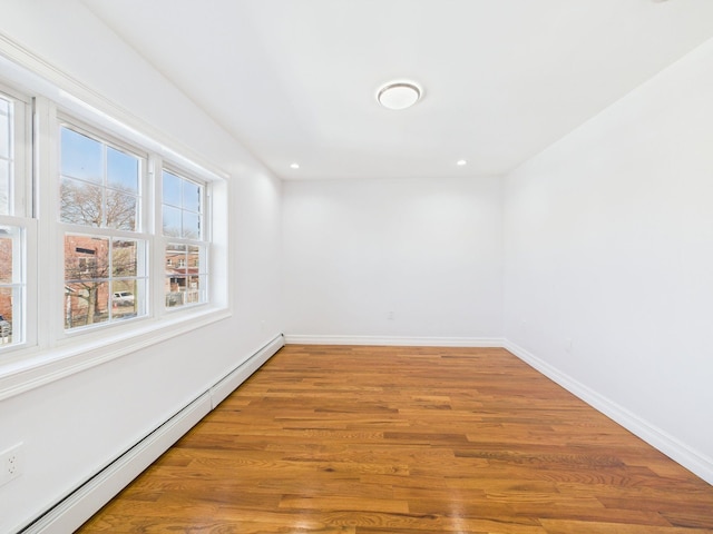 empty room featuring recessed lighting, a baseboard heating unit, baseboards, and wood finished floors