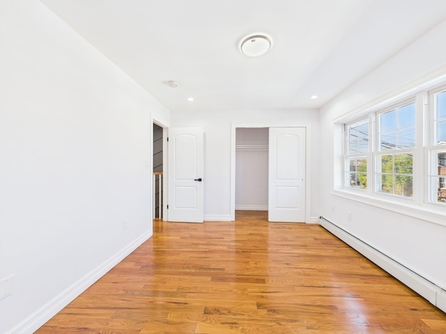 unfurnished bedroom featuring light wood-type flooring, a baseboard heating unit, recessed lighting, a closet, and baseboards