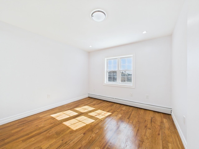 empty room featuring a baseboard heating unit, recessed lighting, baseboards, and hardwood / wood-style floors