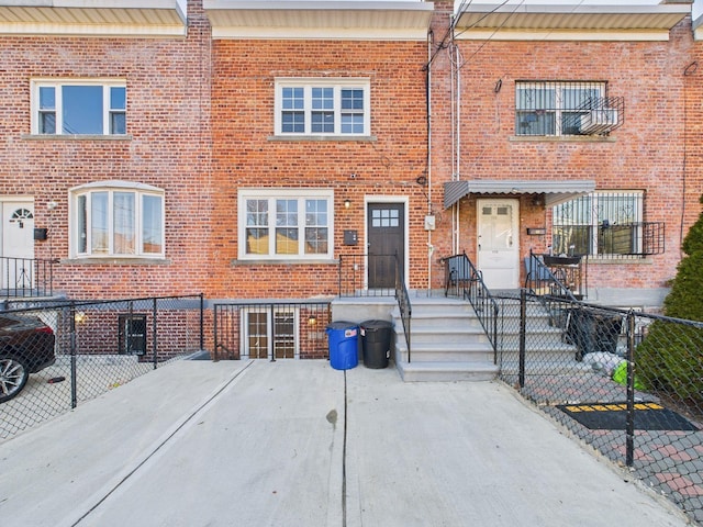 view of property featuring brick siding and fence