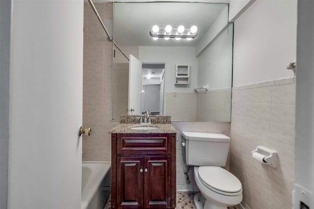 full bath featuring vanity, tile walls, and toilet