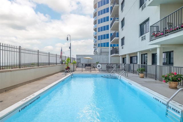 pool with a patio area and fence