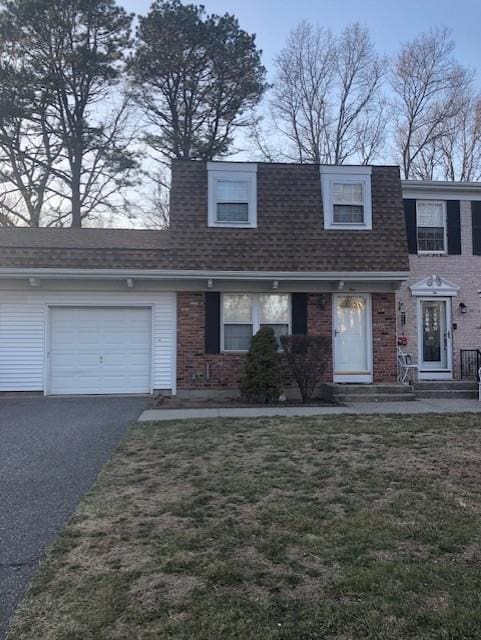 view of front of house featuring an attached garage, a shingled roof, a front lawn, aphalt driveway, and brick siding