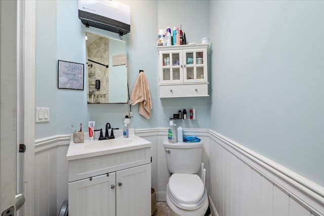 full bathroom with vanity, toilet, a wainscoted wall, and a tile shower