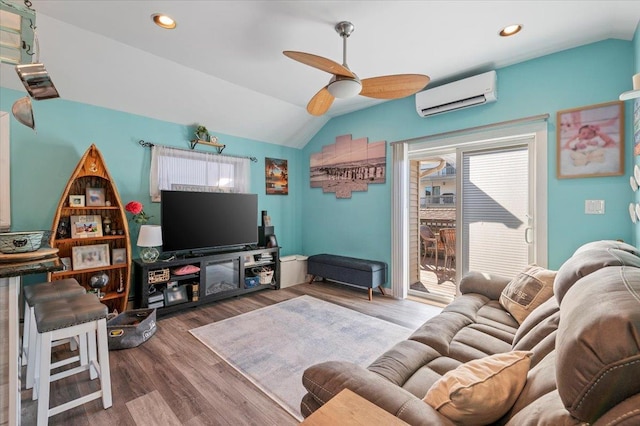 living area with lofted ceiling, wood finished floors, a ceiling fan, and a wall mounted AC