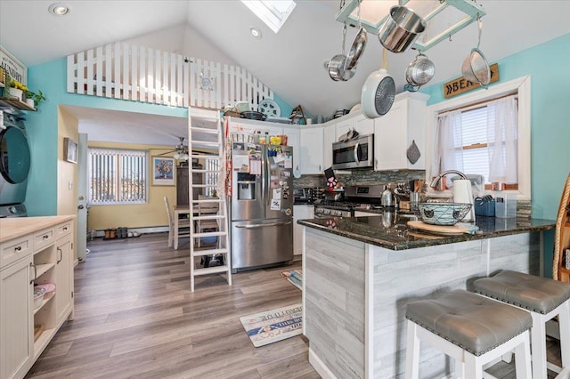 kitchen featuring light wood finished floors, plenty of natural light, appliances with stainless steel finishes, and a skylight