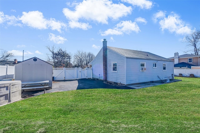 view of property exterior featuring an outbuilding, a gate, a yard, a fenced backyard, and a storage shed