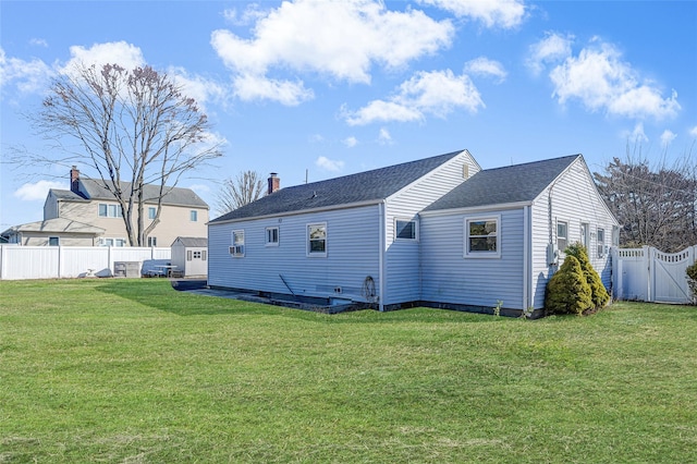 back of property featuring an outbuilding, a lawn, a gate, a fenced backyard, and a storage shed