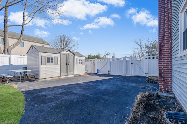 view of yard featuring a storage unit, a gate, fence, an outdoor structure, and a patio area