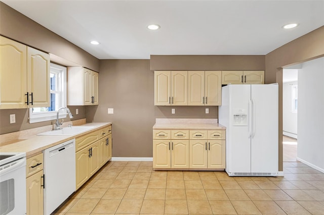 kitchen with a sink, white appliances, light countertops, light tile patterned floors, and baseboards