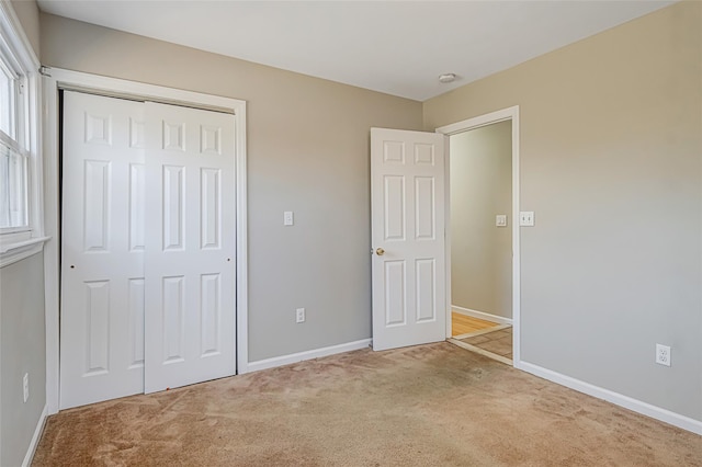 unfurnished bedroom with carpet flooring, baseboards, and a closet