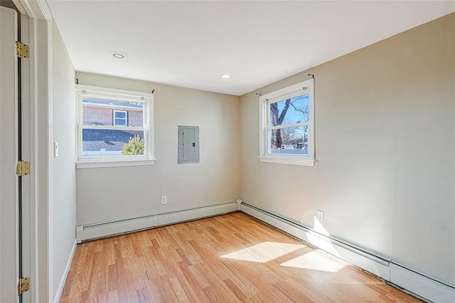 spare room featuring light wood-style flooring, a healthy amount of sunlight, and baseboard heating