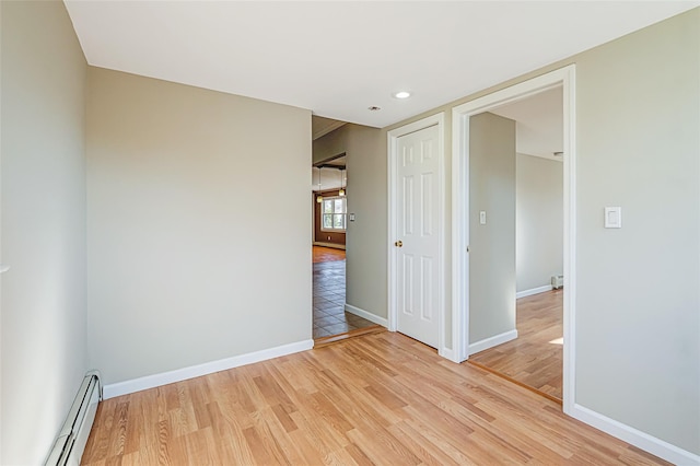 empty room featuring light wood-type flooring, baseboards, and baseboard heating