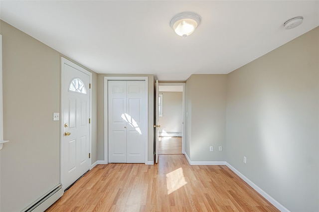 foyer entrance featuring light wood-type flooring, a baseboard heating unit, and baseboards