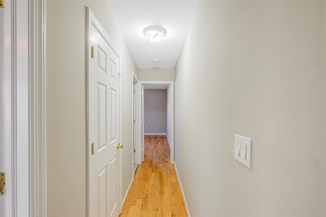 hallway with light wood-type flooring and baseboards