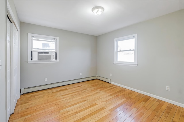 unfurnished room with a wealth of natural light, baseboard heating, cooling unit, and light wood-type flooring