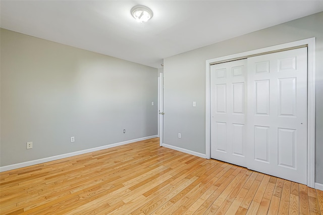 unfurnished bedroom featuring a closet, light wood-style flooring, and baseboards