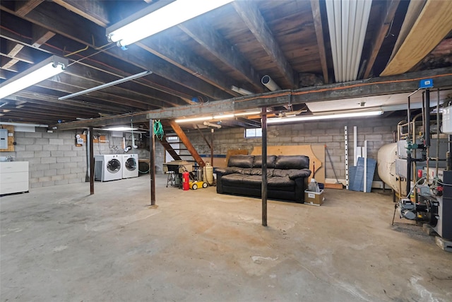 unfinished basement featuring electric panel, washer and dryer, and heating fuel