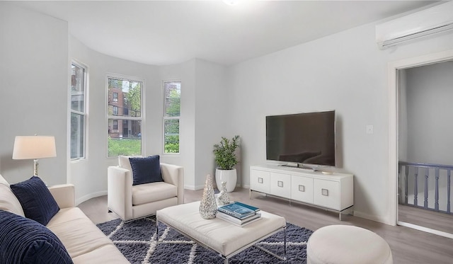 living area with a wall mounted AC, baseboards, and wood finished floors