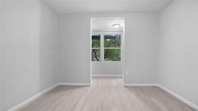 spare room with baseboards and light wood finished floors