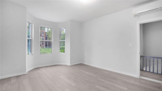 spare room featuring baseboards, wood finished floors, and a wall mounted AC