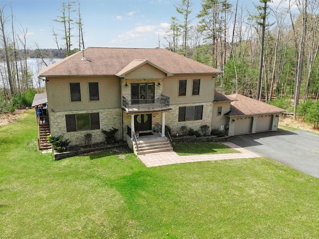 view of front of home with stone siding, a balcony, an attached garage, and a front lawn