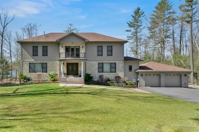 view of front of property with aphalt driveway, stone siding, a front yard, a garage, and a balcony