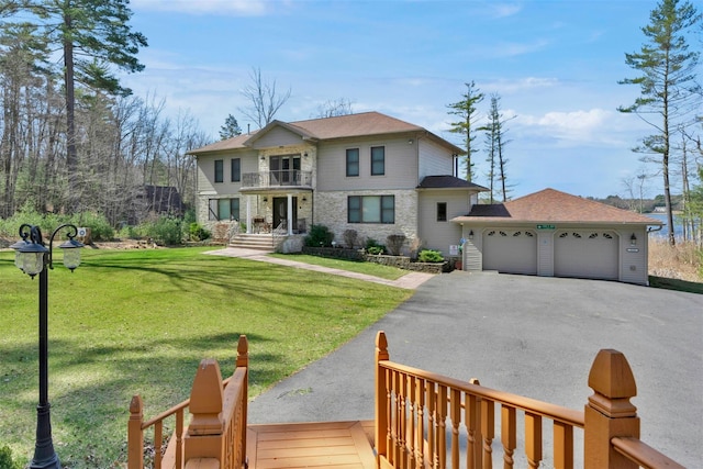 view of front of property featuring a front yard, a balcony, a garage, stone siding, and aphalt driveway