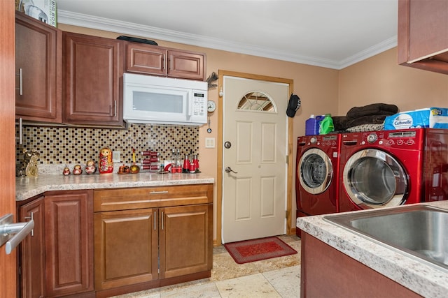 clothes washing area featuring washer and dryer, cabinet space, crown molding, and a sink