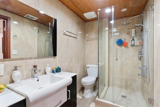 bathroom featuring vanity, a shower stall, tile walls, and visible vents