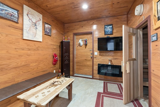 interior space featuring a glass covered fireplace, wooden ceiling, recessed lighting, and wood walls