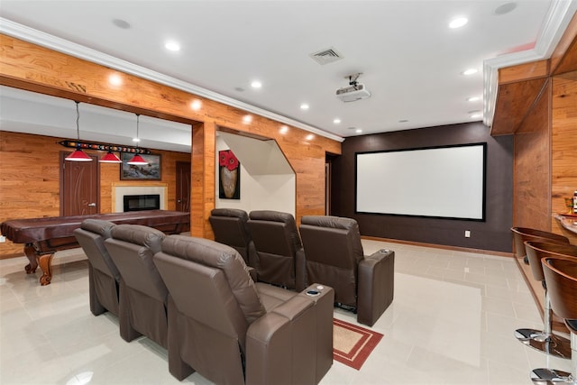 home theater room with visible vents, a glass covered fireplace, recessed lighting, wood walls, and crown molding