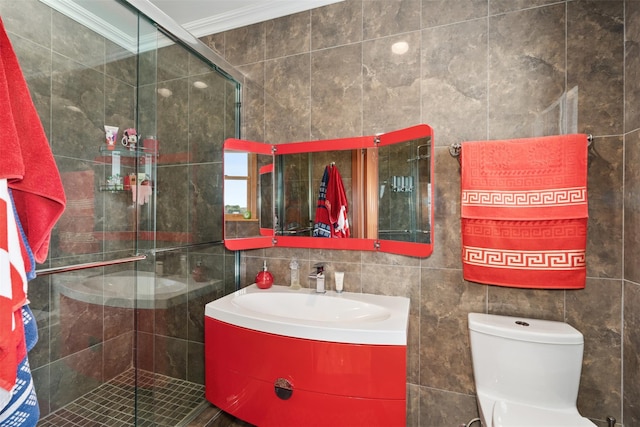 full bath featuring toilet, vanity, ornamental molding, a stall shower, and tile walls