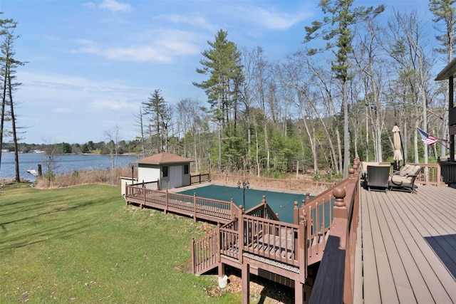 deck featuring a yard, a water view, and an outbuilding