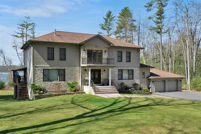 view of front of home with driveway, stone siding, an attached garage, a front yard, and a balcony