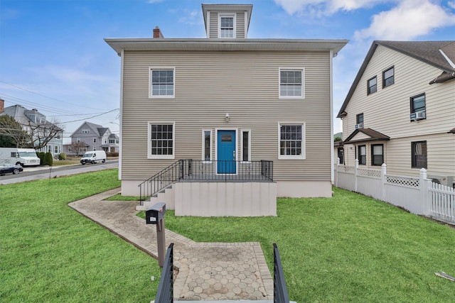 rear view of house featuring a yard and fence