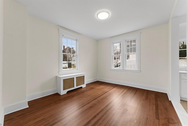 spare room with baseboards, a healthy amount of sunlight, and wood finished floors