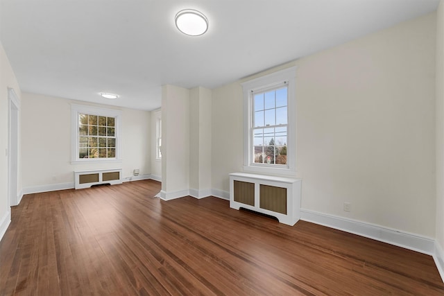 unfurnished room with radiator heating unit, dark wood-style floors, and baseboards