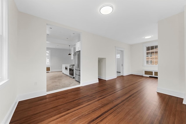 unfurnished living room featuring baseboards and dark wood-style flooring