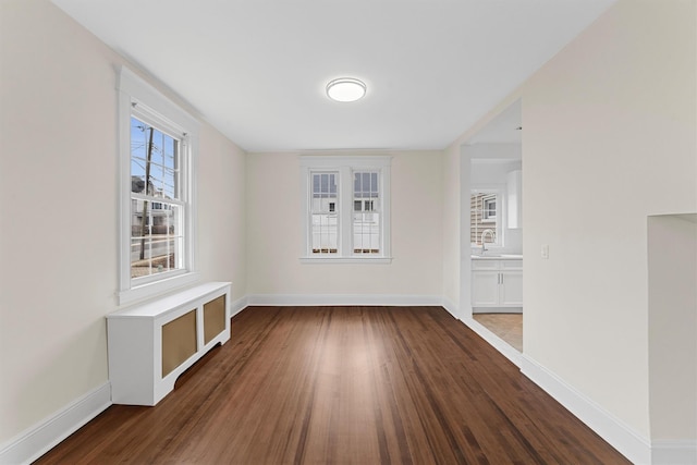 spare room with wood finished floors, baseboards, and a sink