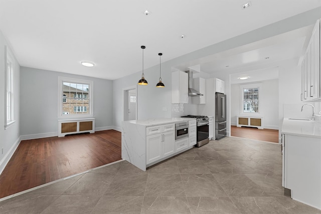 kitchen featuring a sink, wall chimney range hood, radiator heating unit, and stainless steel appliances