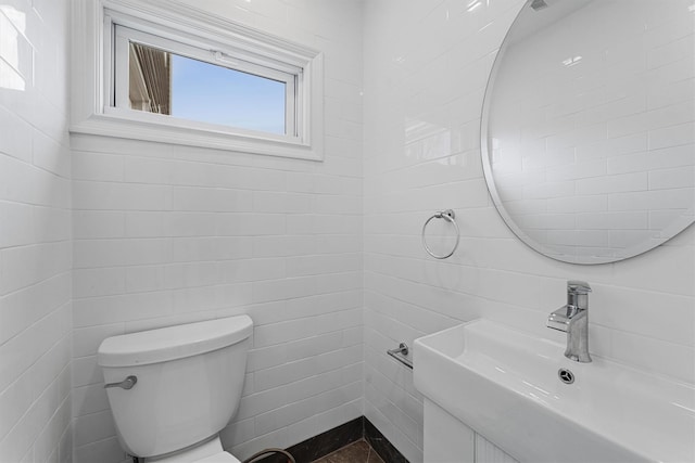 bathroom featuring a sink, toilet, and tile walls