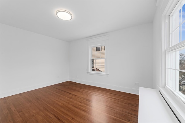 unfurnished room with baseboards and dark wood-style floors