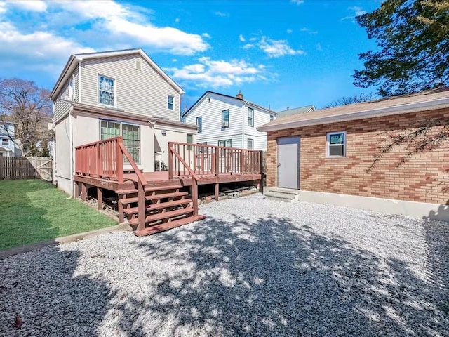 rear view of house featuring a yard, brick siding, a deck, and fence