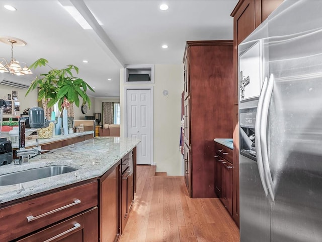 kitchen with light stone countertops, recessed lighting, light wood-style floors, stainless steel refrigerator with ice dispenser, and a sink