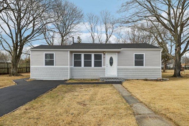 view of front facade with entry steps, a front lawn, fence, and aphalt driveway